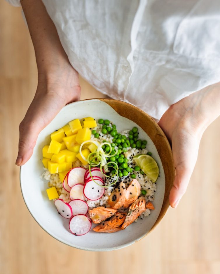Bowl com salmão, legumes e grãos servido nas mãos